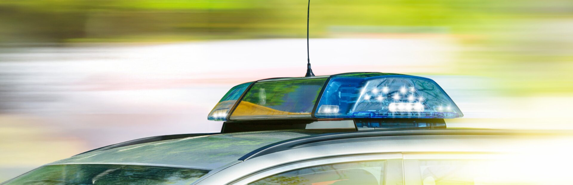 Dach eines Polizeiauto mit Blaulicht vor verschwommenem Hintergrund | © Foto: AdobeStock #203049376 | jozsitoeroe