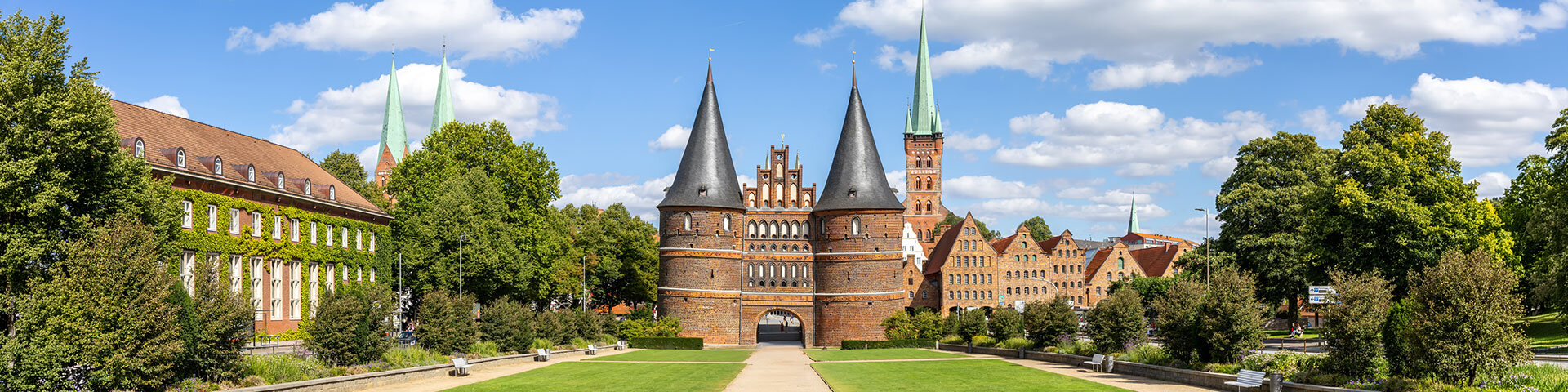 Ein Panoramfoto des Holstentors in Lübeck bei sonnigem Wetter | © Foto: AdobeStock #1179261800 | Markus Mainka